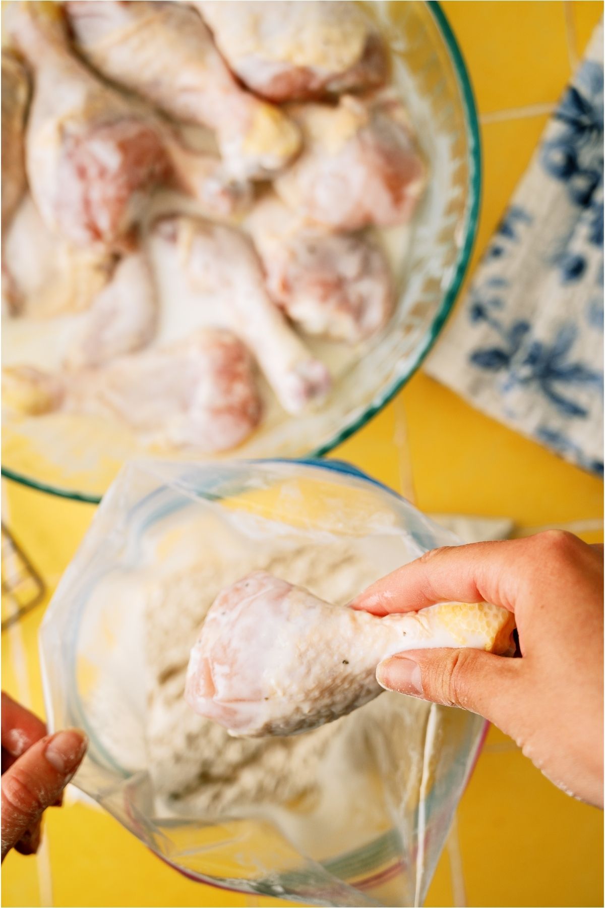 Placing a chicken piece in a ziplock bag filled with seasonings.