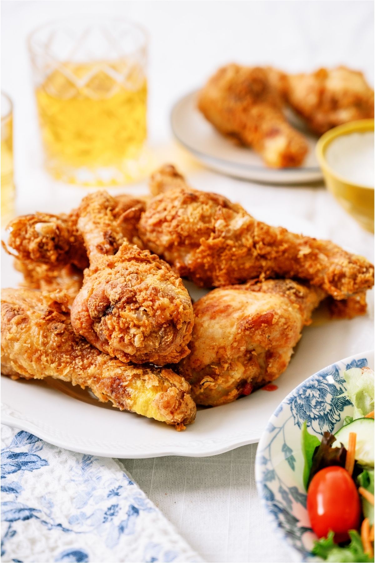 Crispy Fried Chicken on a plate with a drink in the background.