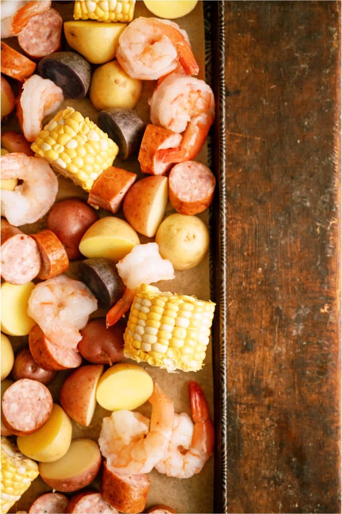 Sheet Pan Shrimp Boil ingredients mixed together on a sheet pan.