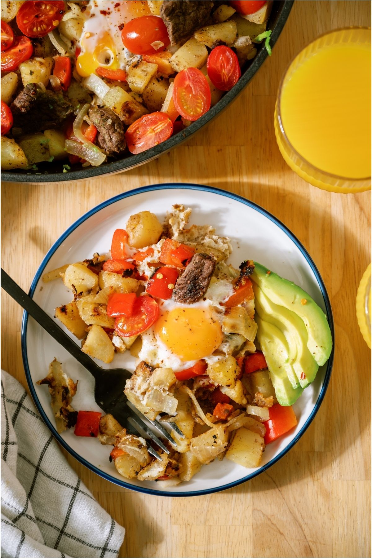 A plate with a serving of Steak and Eggs Skillet with the skillet in the background.
