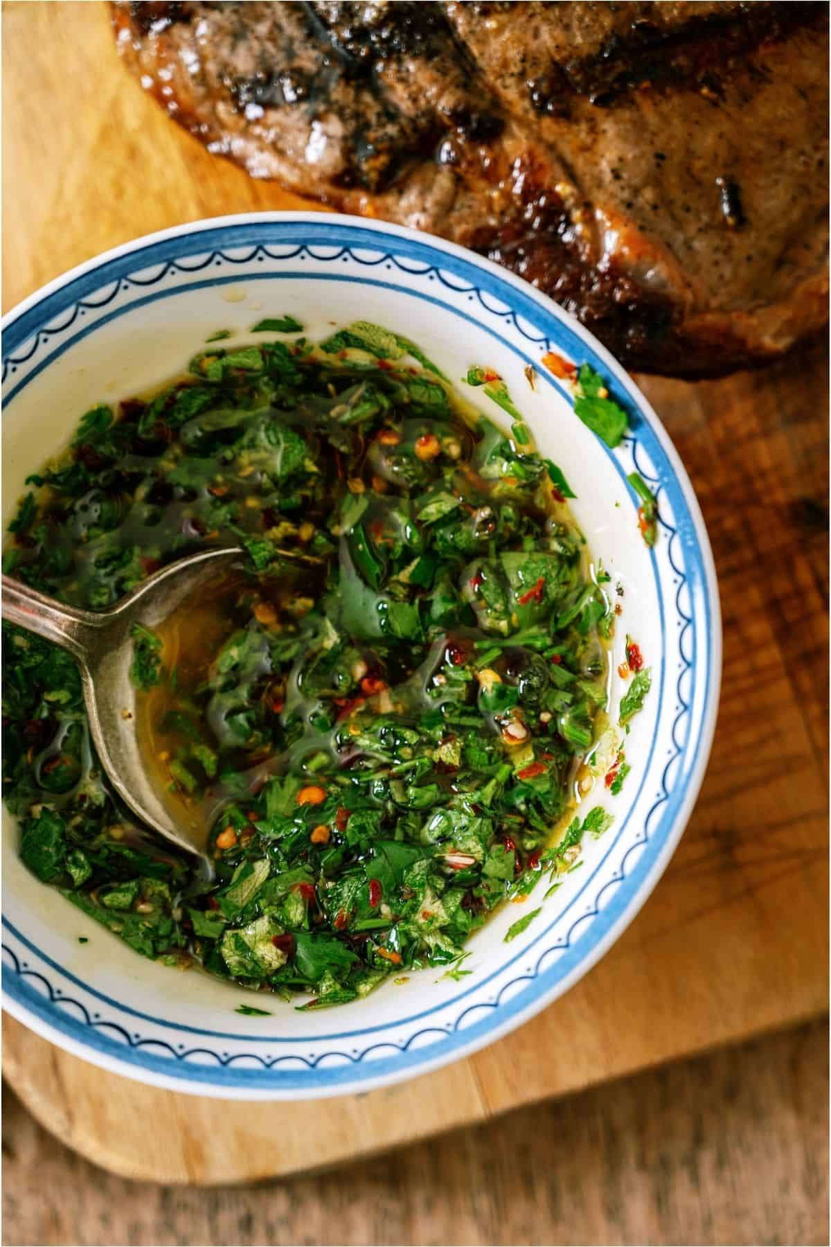 Top view of a bowl of Chimichurri Sauce with a spoon.