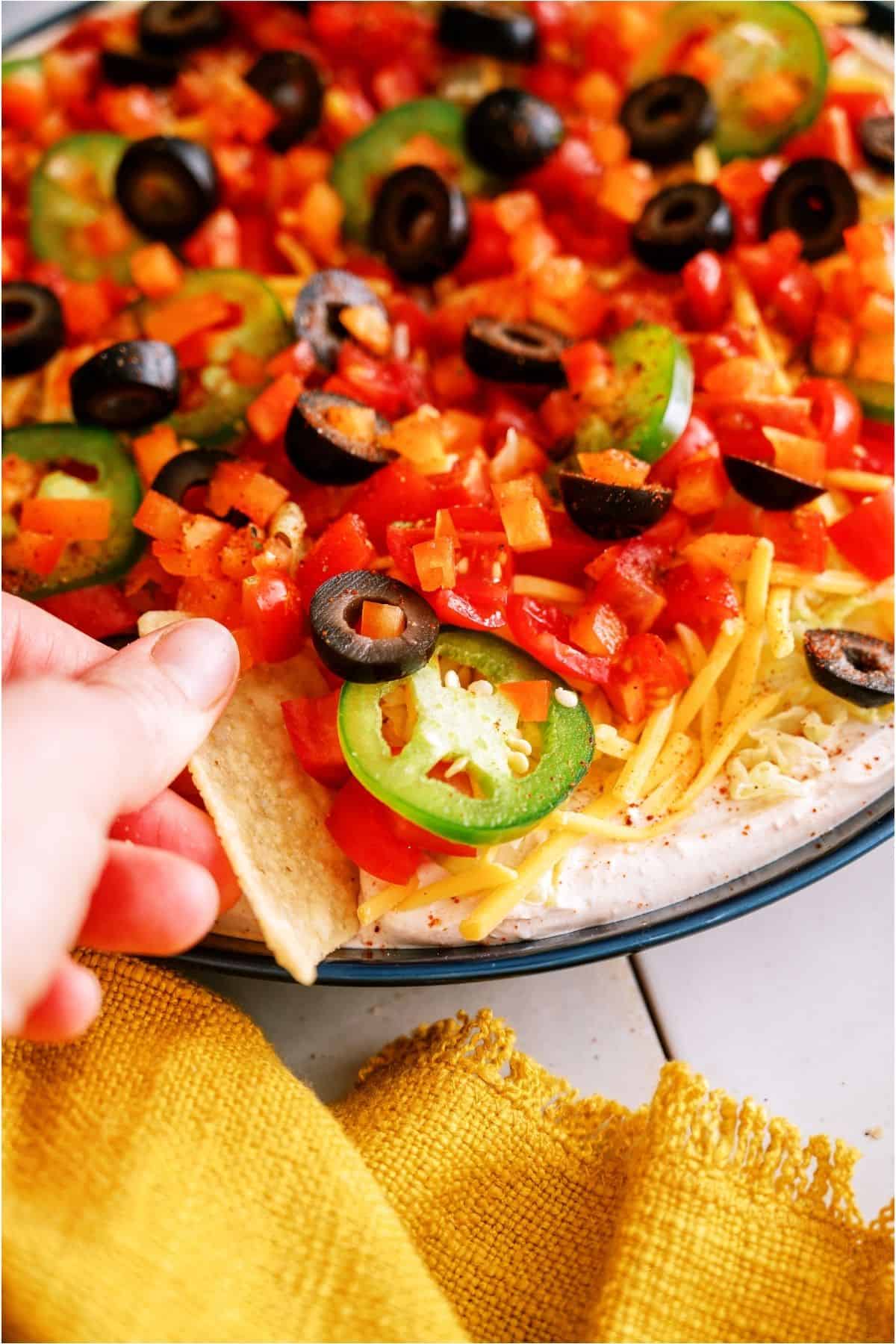 A chip scooping a bite of Easy Taco Dip off the platter.