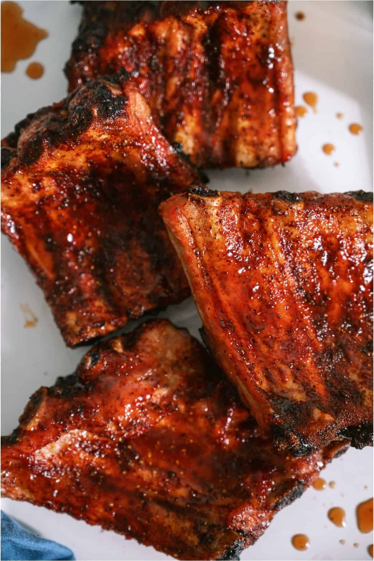Close up of Grilled Baby Back Ribs pieces on a white serving platter.
