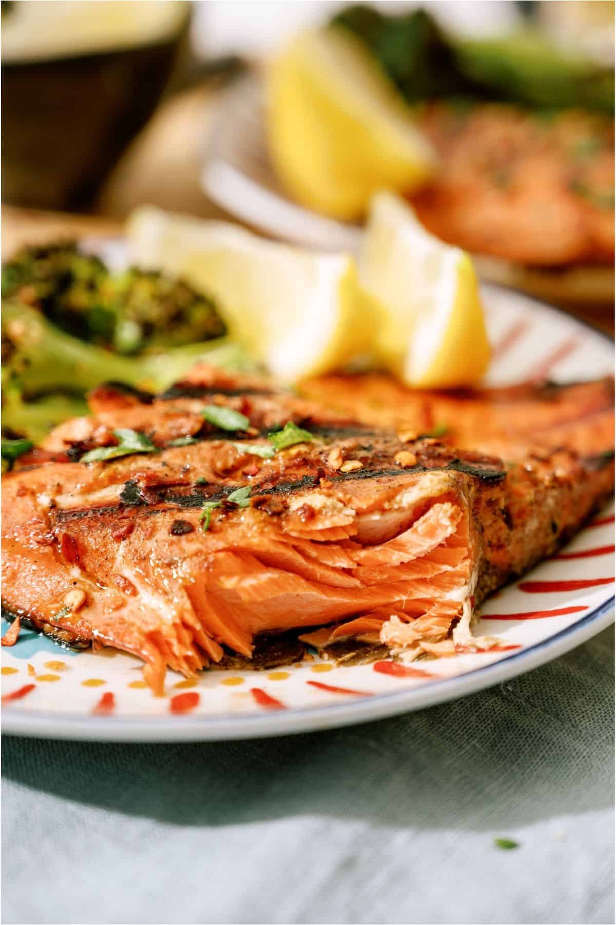 A plate of grilled salmon with a bite missing and broccoli.
