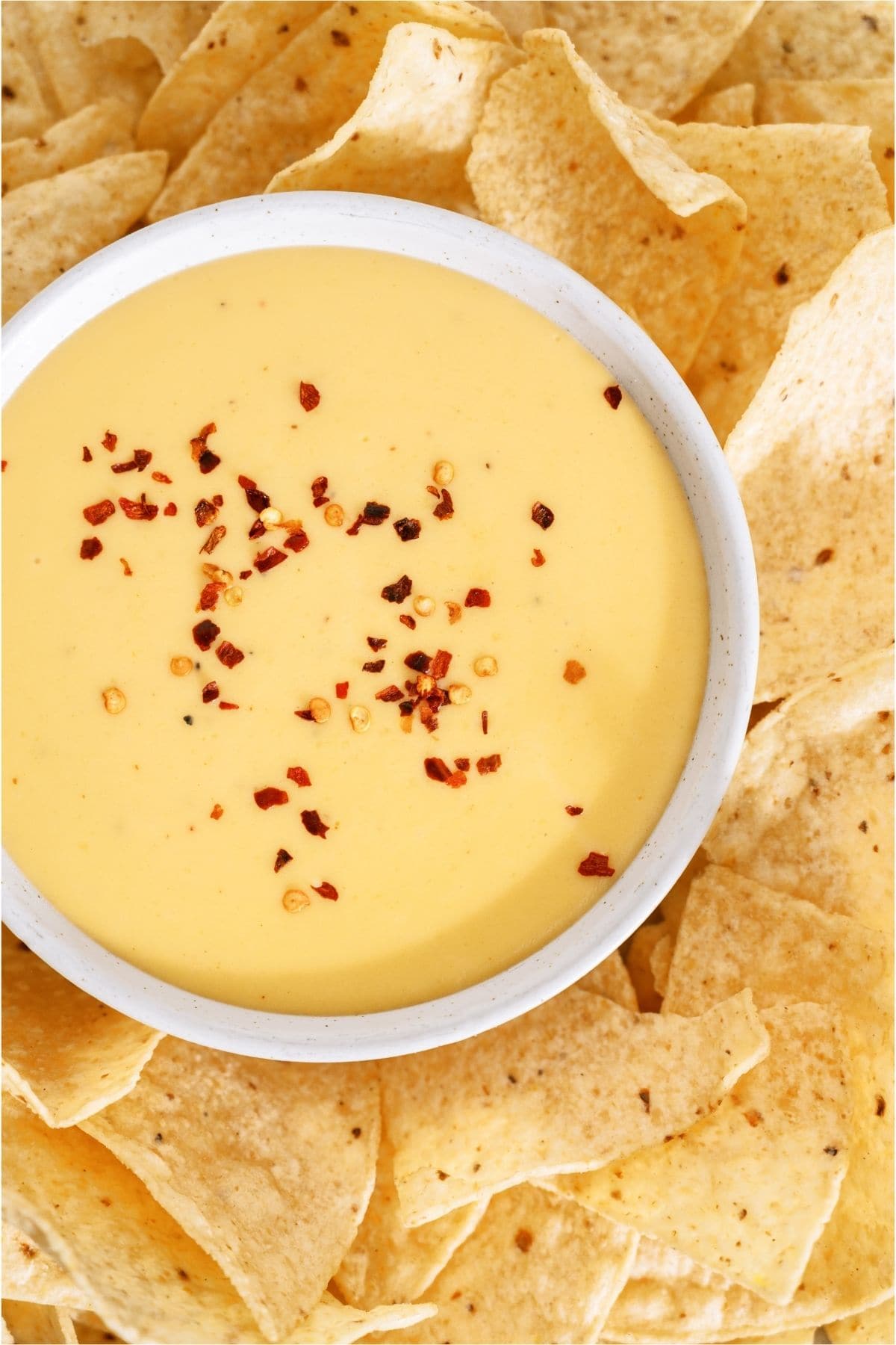 Top view of Quick Nacho Cheese Sauce in a bowl sprinkled with red pepper flakes.