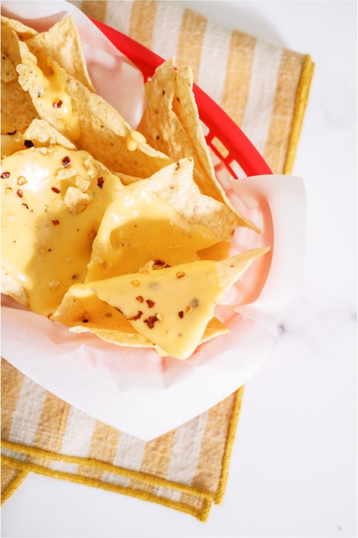 Tortilla chips in a basket covered with Quick Nacho Cheese Sauce.