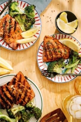 Top view of 3 plates of Grilled Salmon with a side of broccoli.