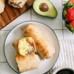Loaded Breakfast Burritos on a plate with one cut in half.