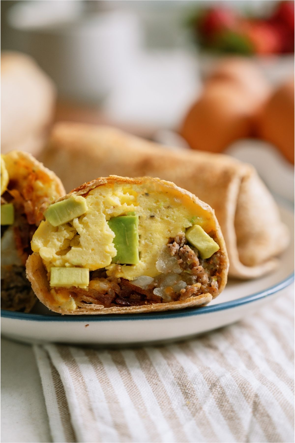 A Loaded Breakfast Burritos on a plate cut in half to show the inside.
