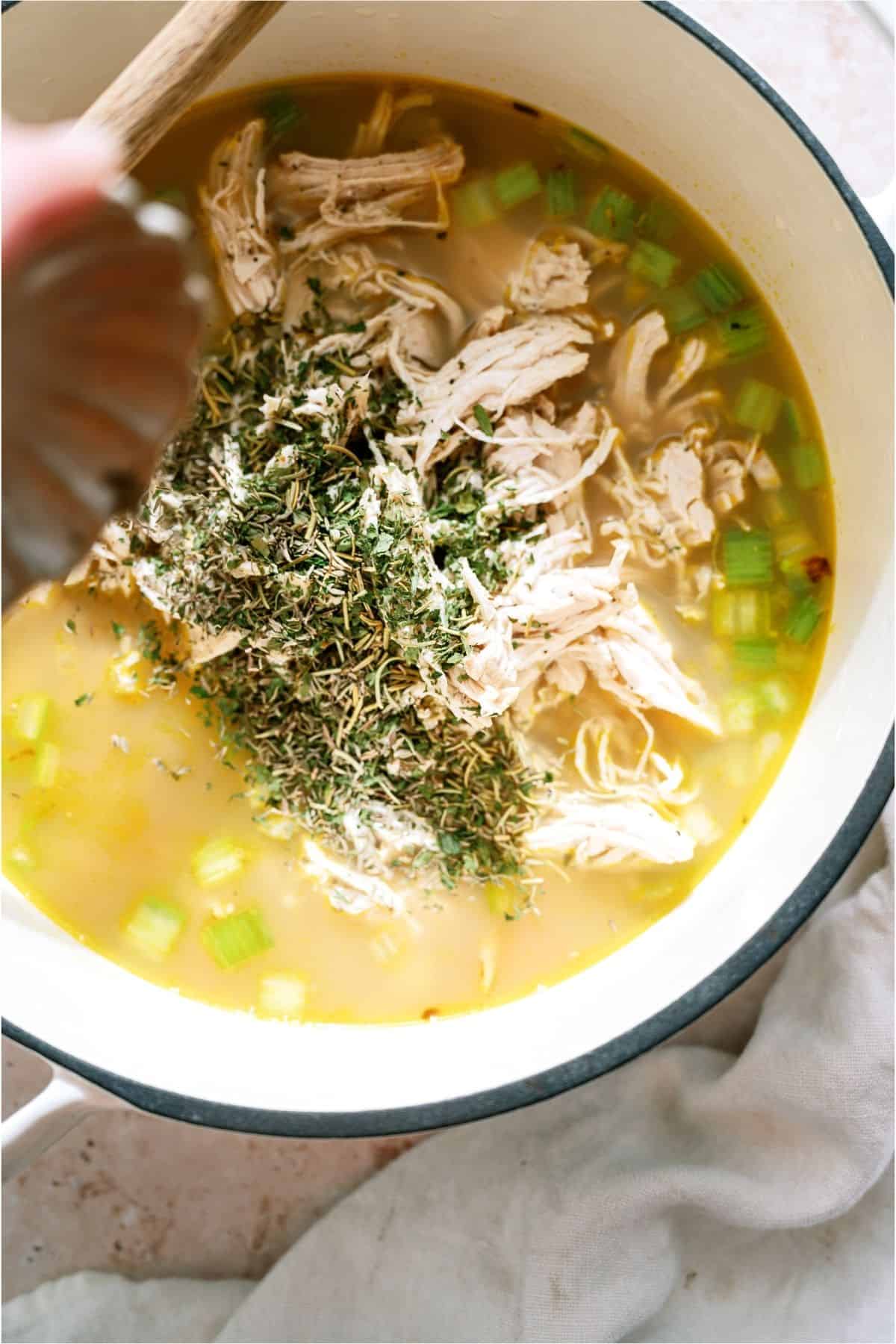 Adding seasoning and shredded chicken to stock pot.