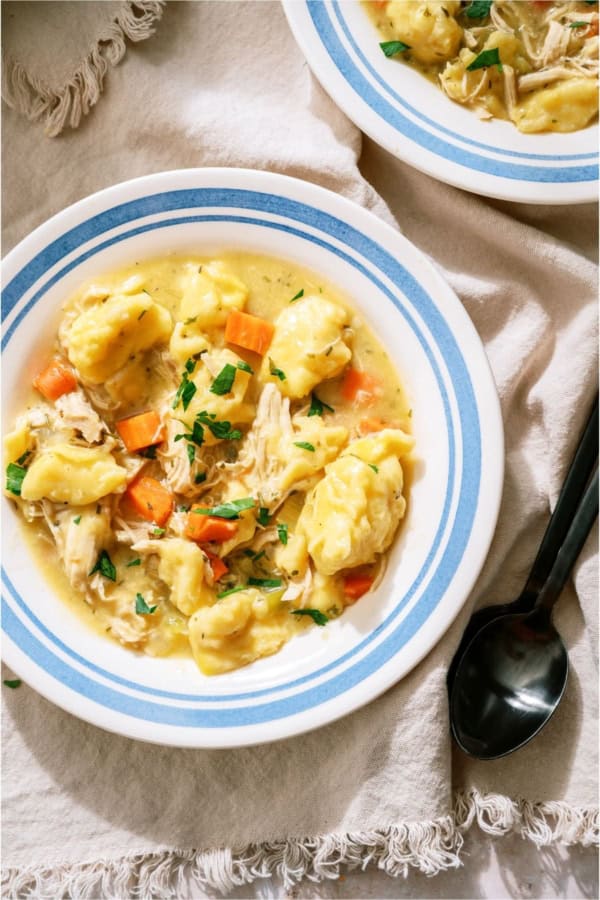 A bowl of 20-Minute Chicken and Dumplings soup with a spoon on the side.