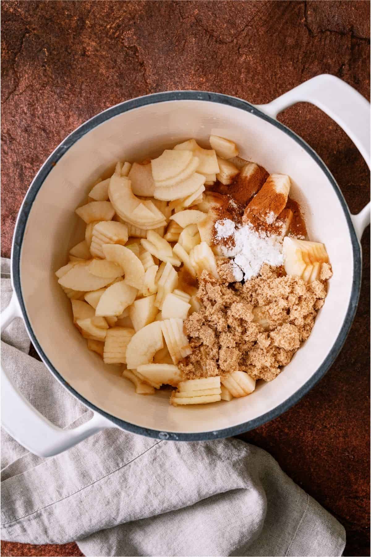 Sliced apples in a saucepan with sugar.