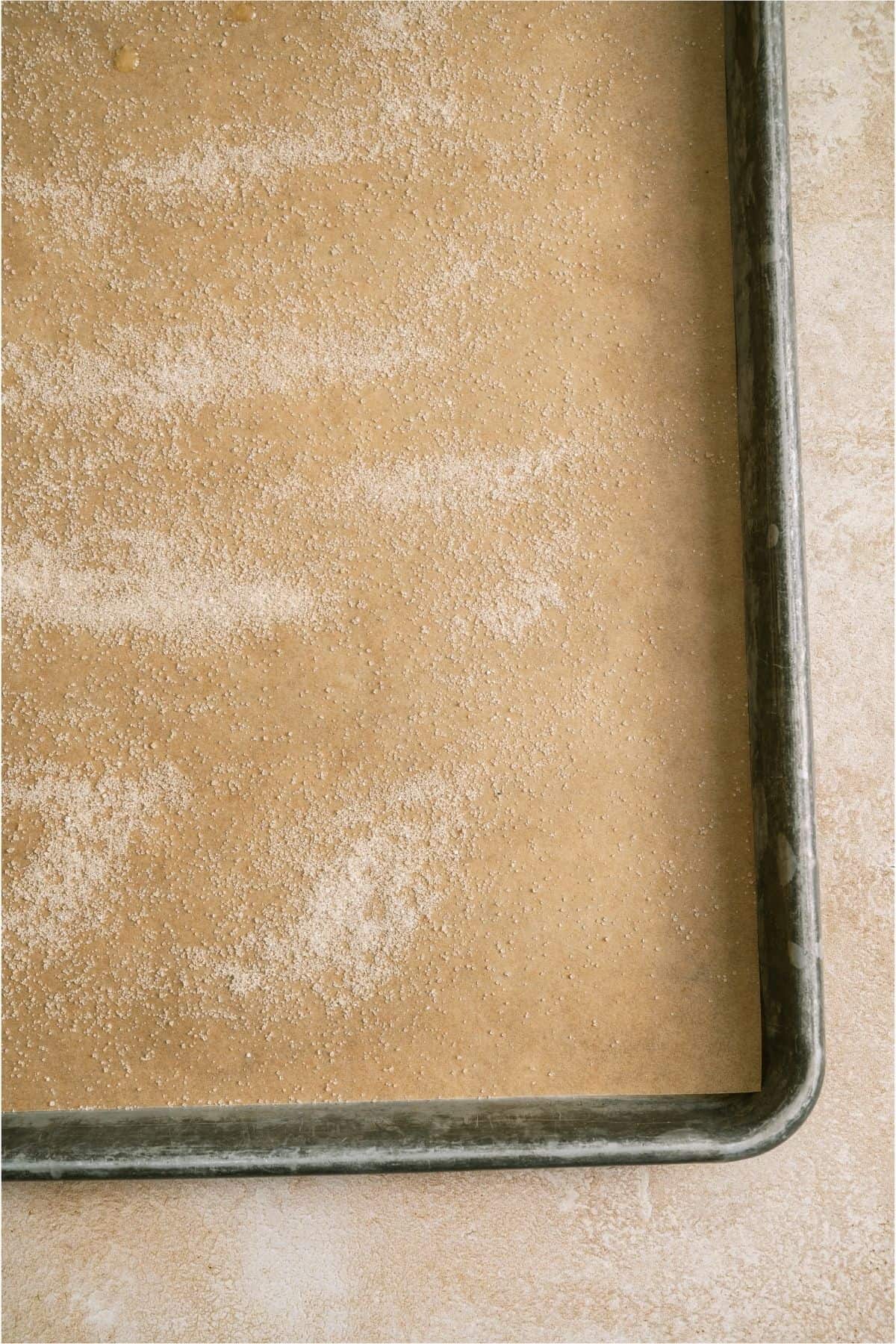 A sheet pan lined with parchment paper and sprinkled with sugar.