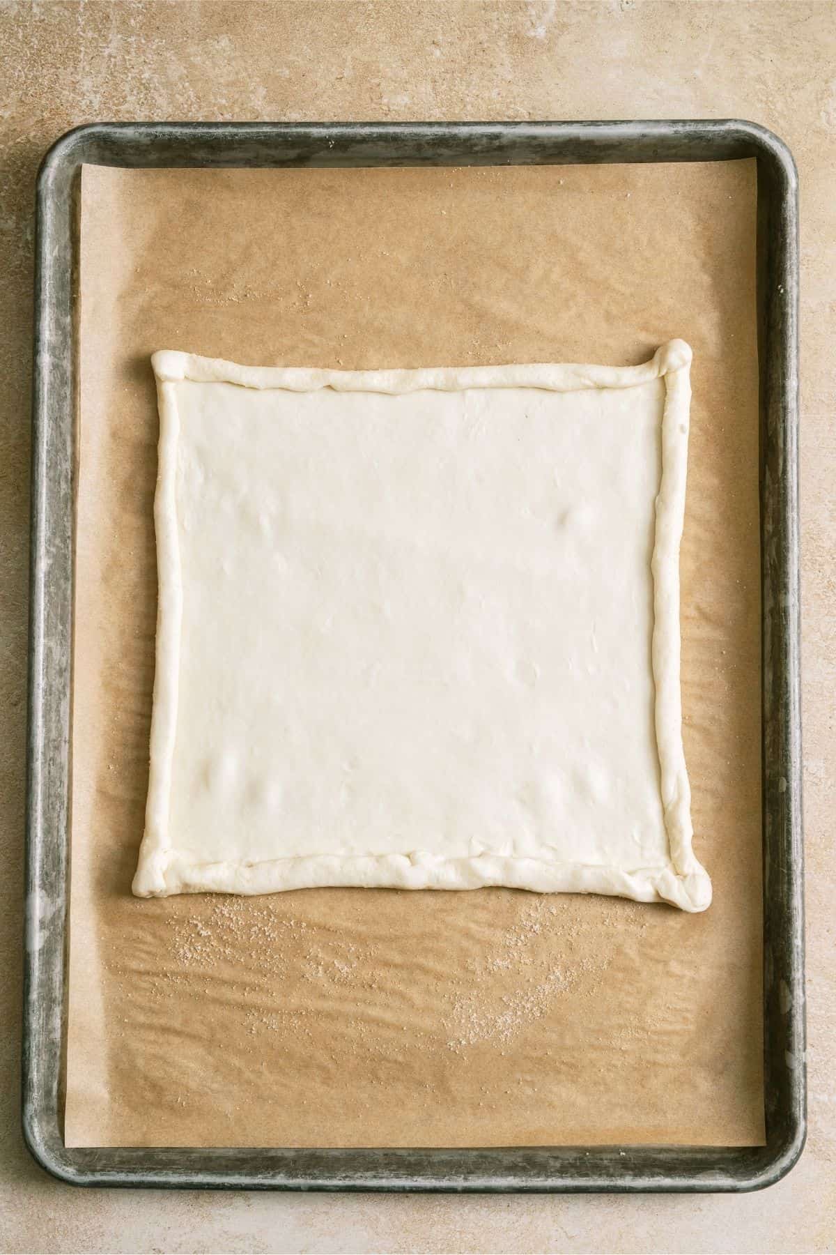 Puff Pastry square on top of sugar on sheet pan.