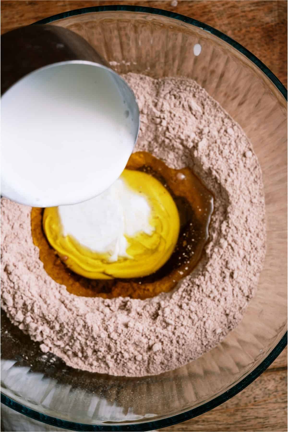 Adding wet ingredients to cake mix in a bowl.