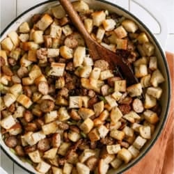 Top view of a bowl of Easy Sausage & Herb Stuffing with a wooden spoon.