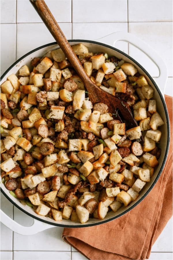 Top view of a bowl of Easy Sausage & Herb Stuffing with a wooden spoon.
