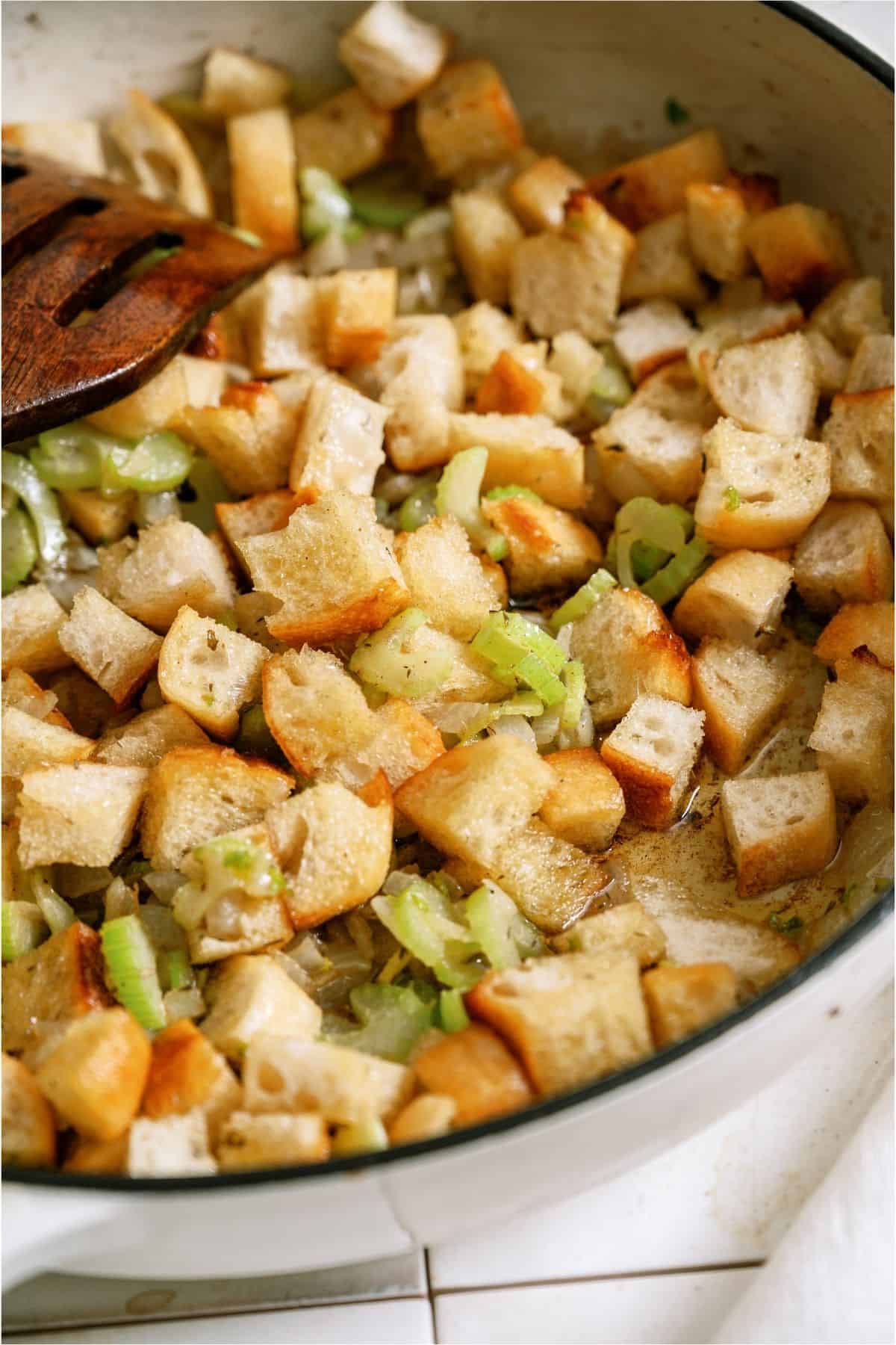 Adding cubed bread to skillet.