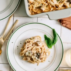 A serving of Homemade Turkey Tetrazzini on a white plate with the remaining casserole in the background.