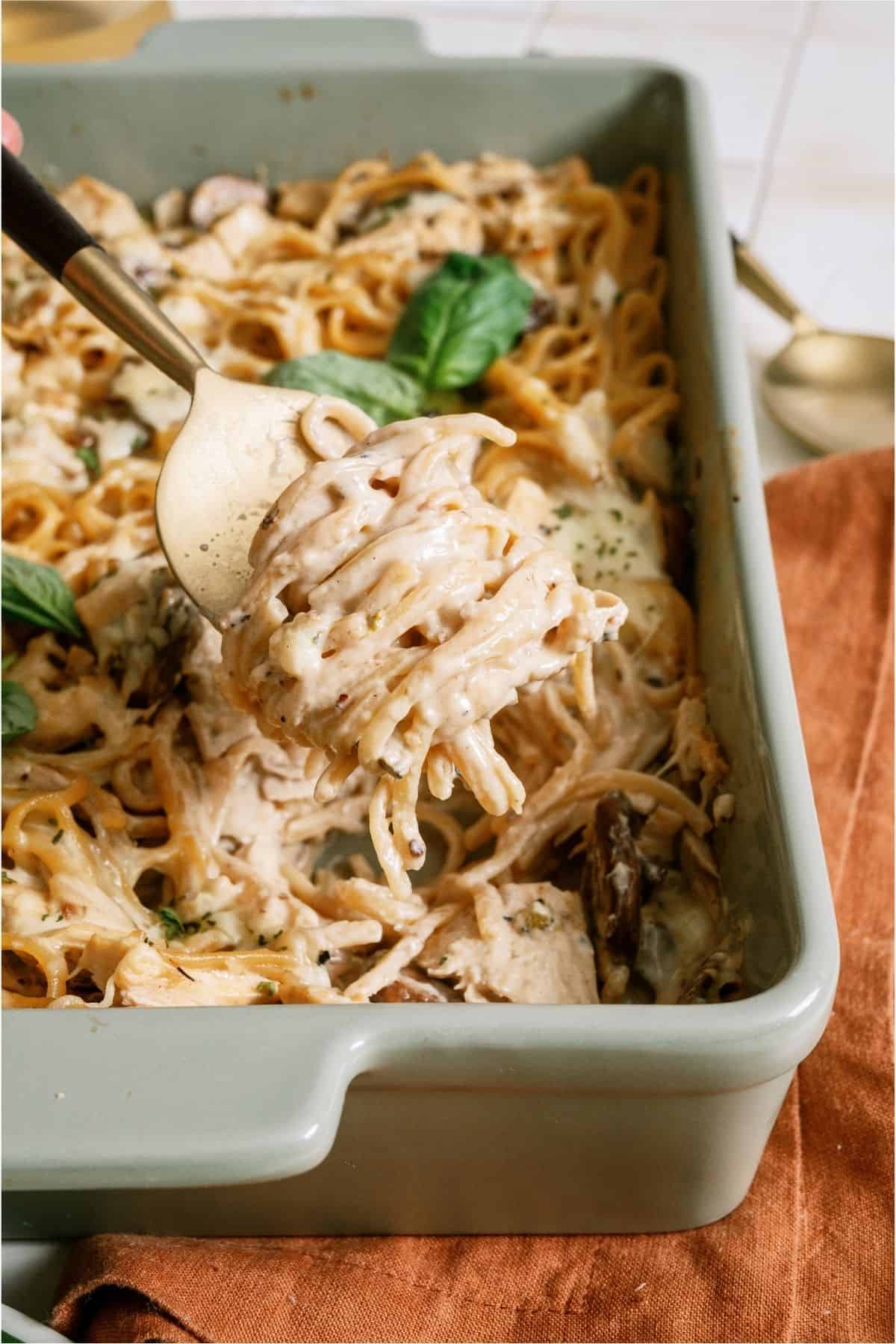 A fork lifting a serving of Homemade Turkey Tetrazzini out of a casserole dishl.