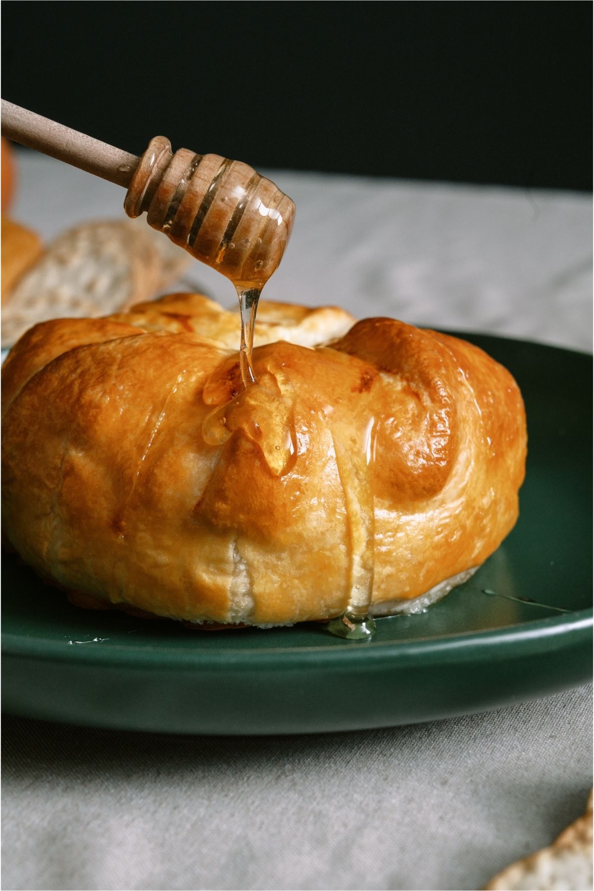 Dripping honey on to  Baked Brie on a serving plate.