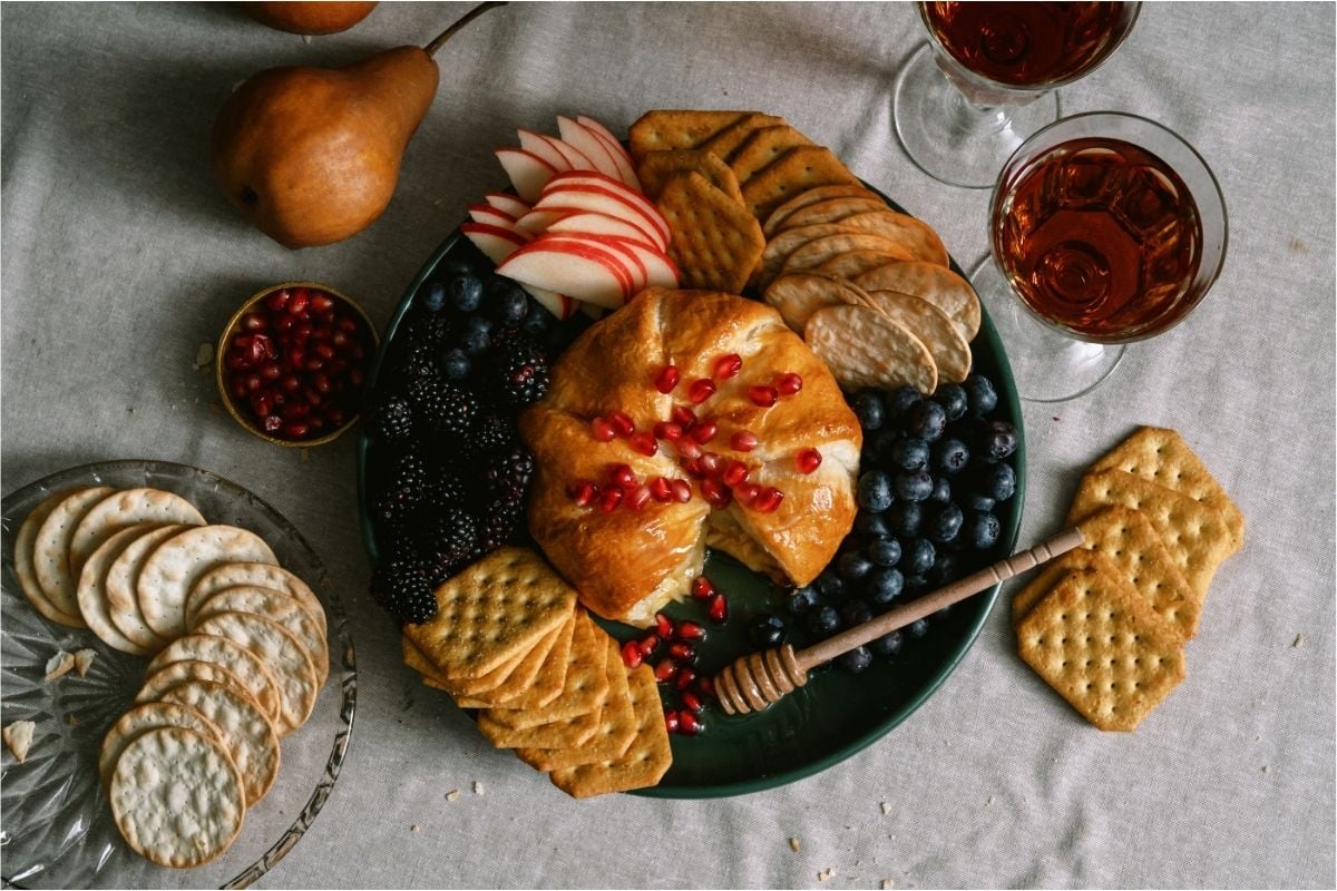 Baked Brie on a serving plate with fruit and crackers.