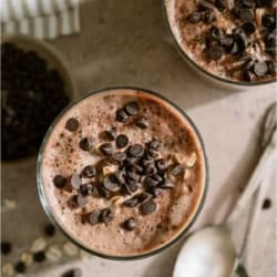Top view of 2 glasses of Healthy Chocolate Overnight Oats topped with chocolate chips and spoons on the side.