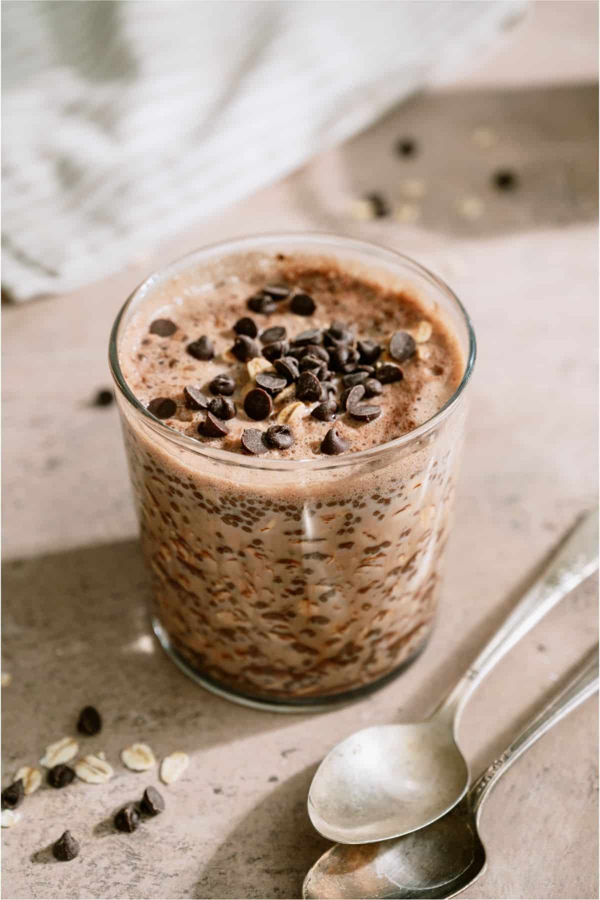 A clear jar of Healthy Chocolate Overnight Oats topped with chocolate chips.