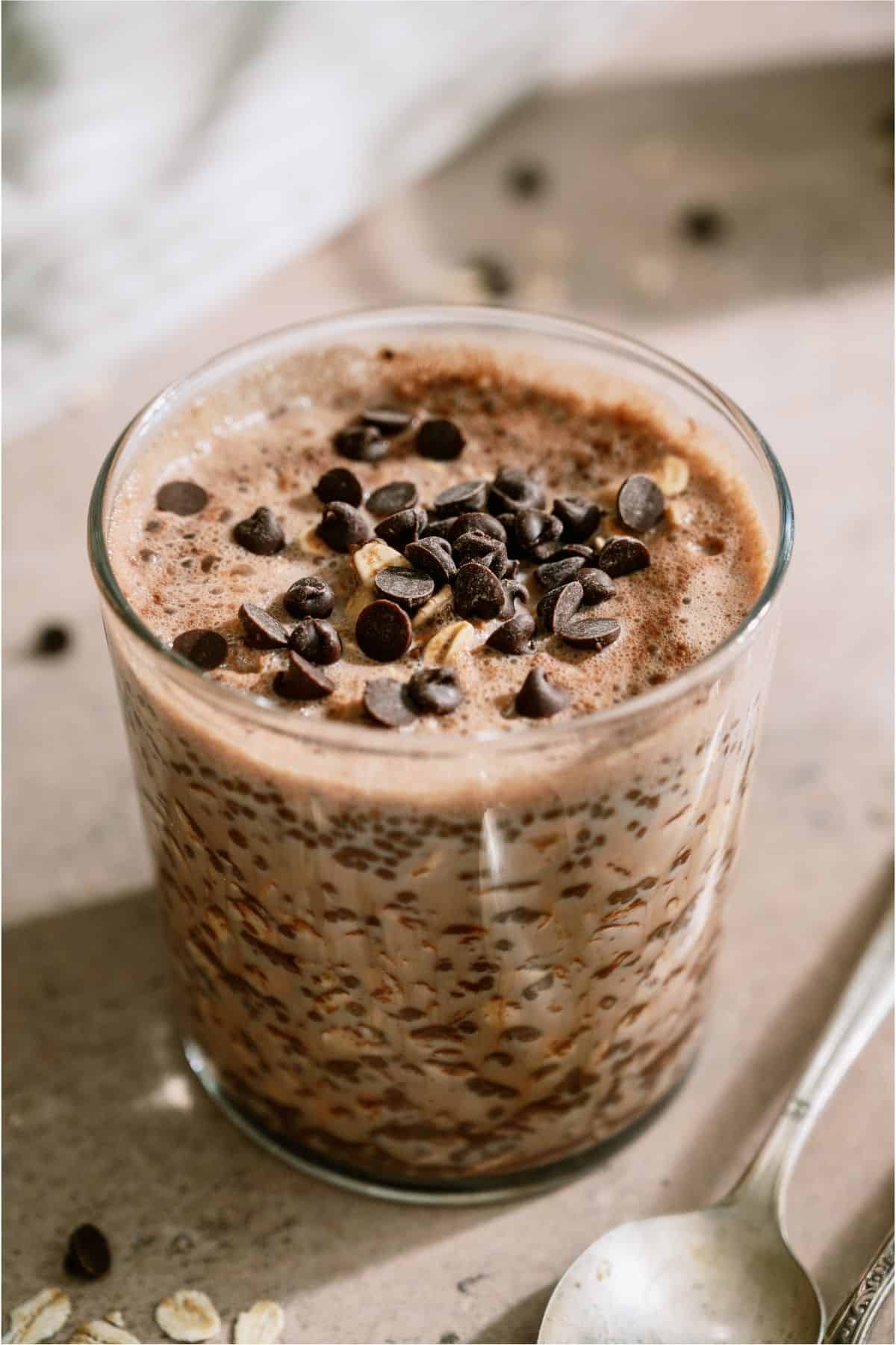 A glass jar of Healthy Chocolate Overnight Oats topped with chocolate chips.