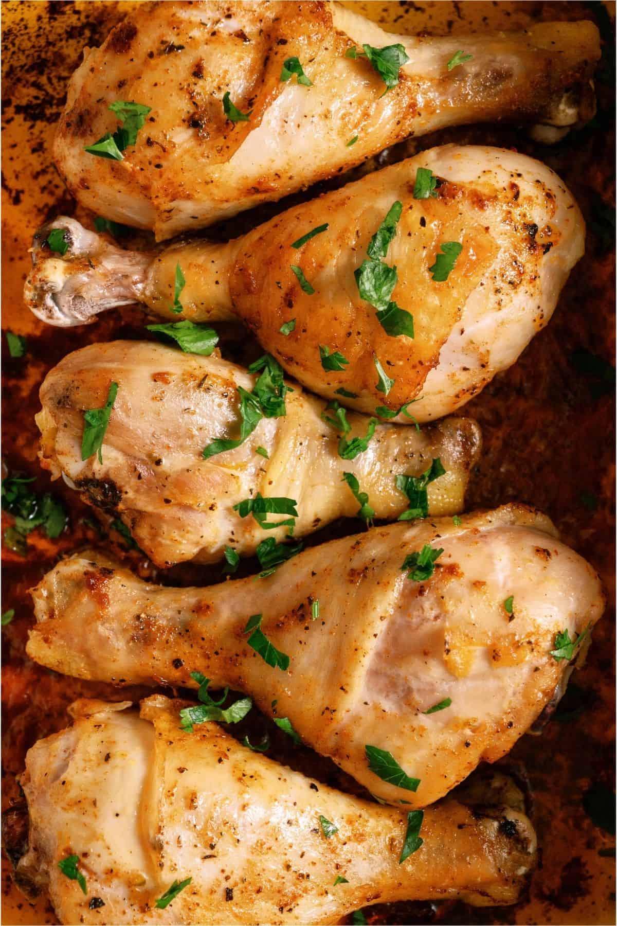 Close up of Juicy Baked Chicken Legs in a baking dish.