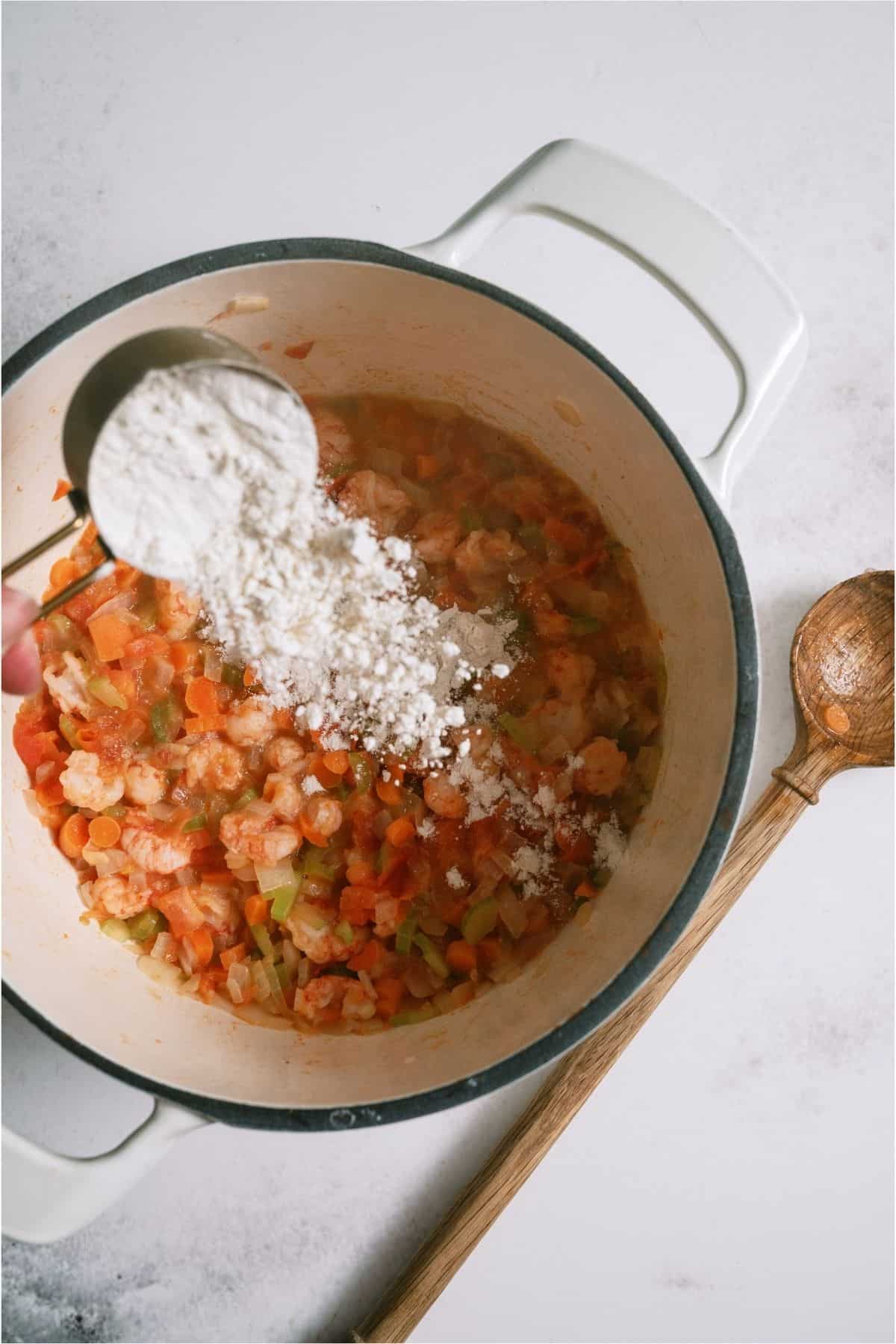 Sprinkling ingredients in stock pot with flour.