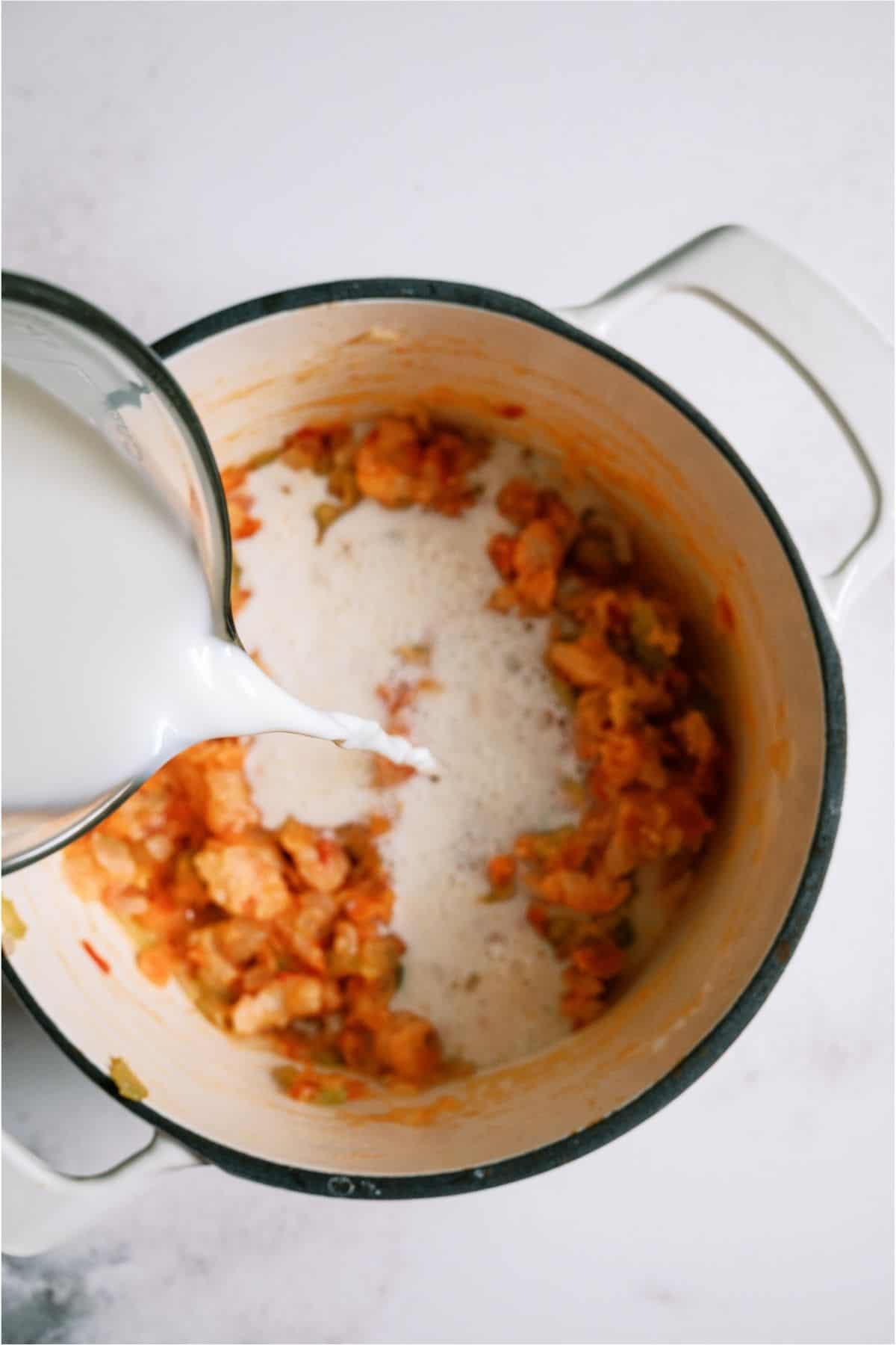 Adding milk to stockpot.