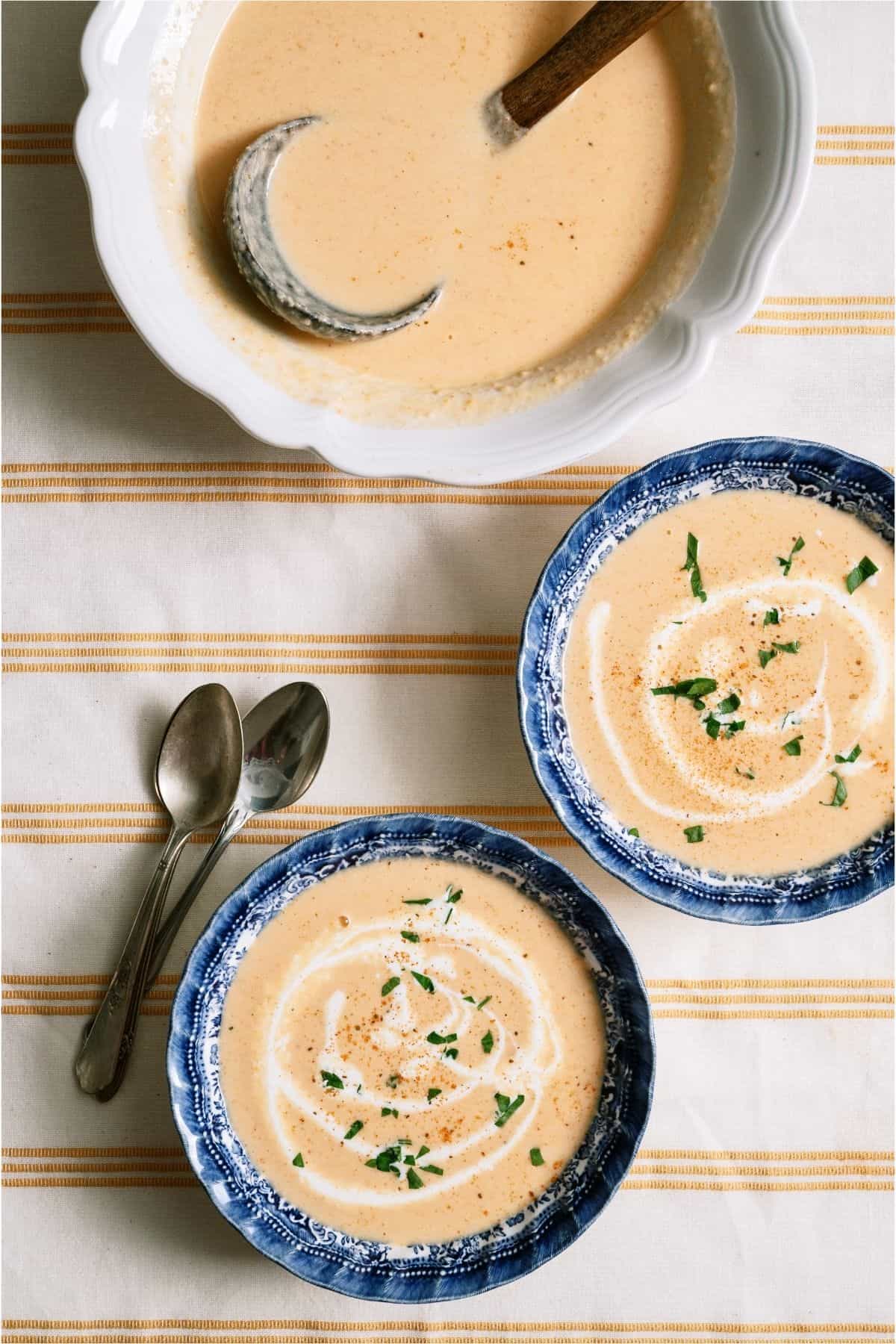 Top view of two bowls of Lobster Bisque with a large serving bowl of Lobster Bisque.