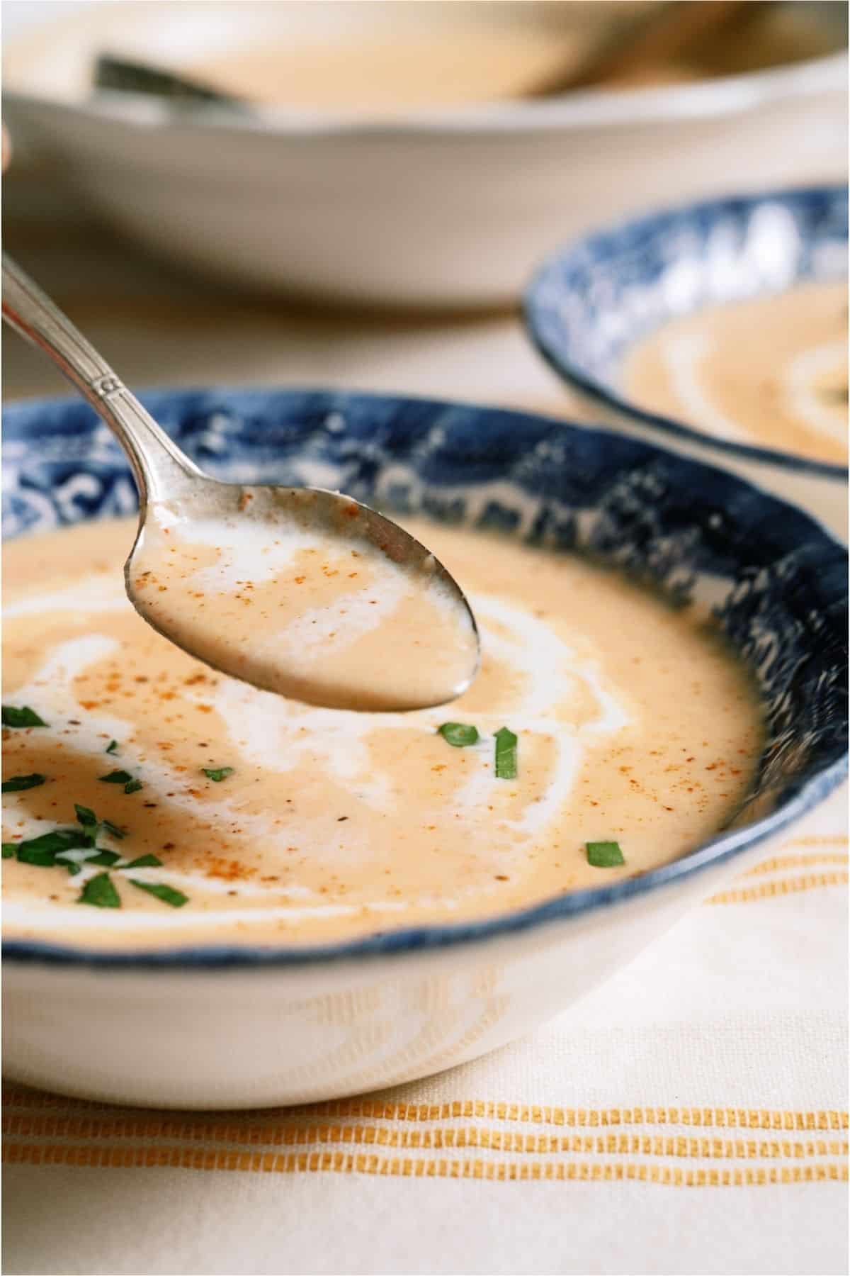 A spoon lifting up a bite of Lobster Bisque from a bowl.