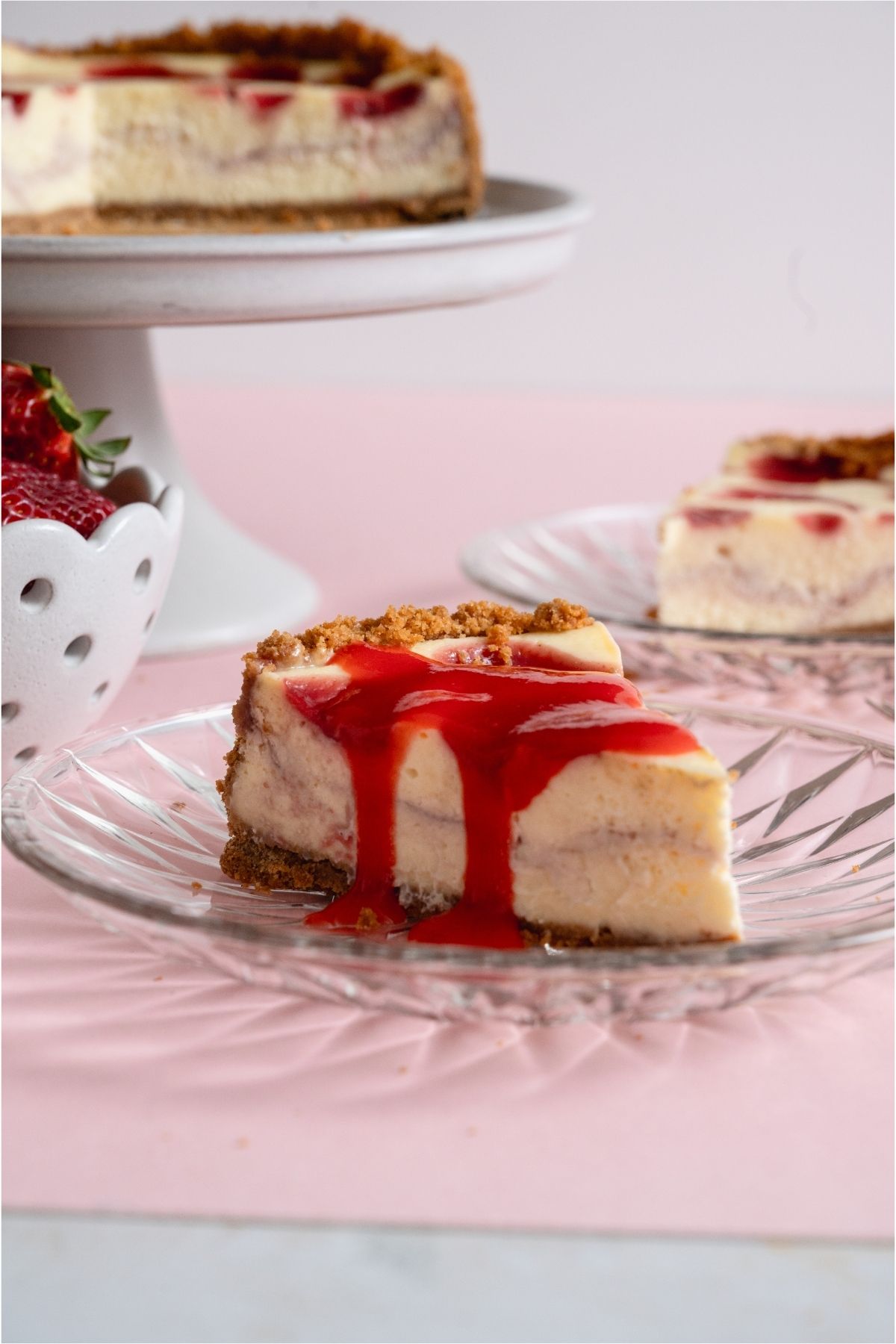 A slice of Classic Strawberry Cheesecake topped with strawberry sauce.
