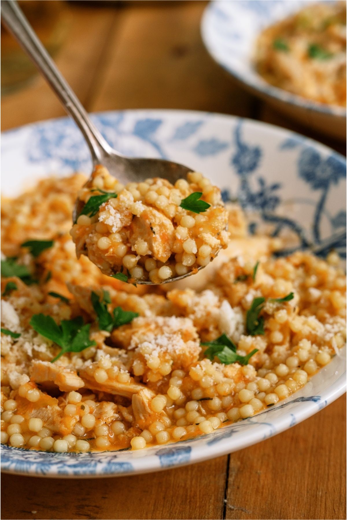 A spoon lifting a bite of Pastina Soup out of a bowl.
