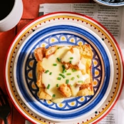 A slice of Eggs Benedict Casserole on a plate topped with Hollandaise sauce and chives.