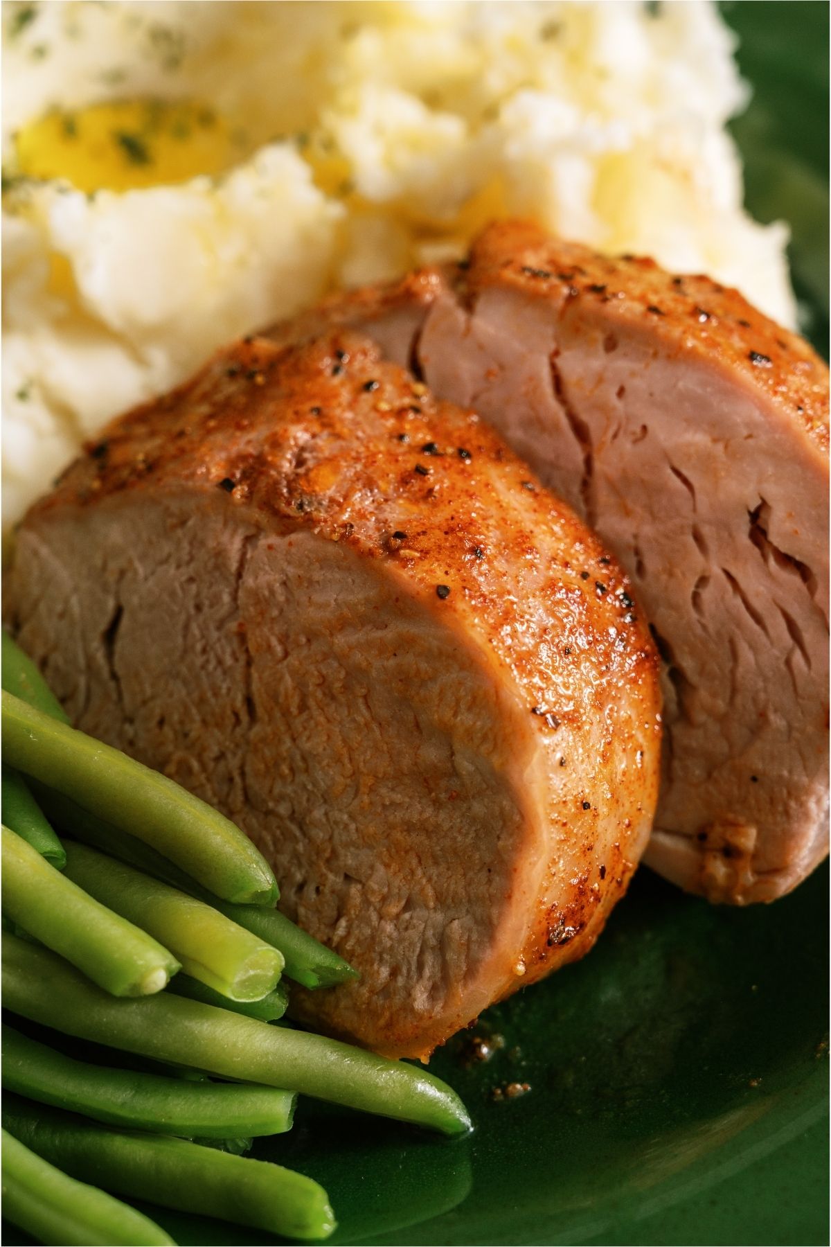 Close up of 2 slices of Oven Baked Pork Tenderloin on a plate.