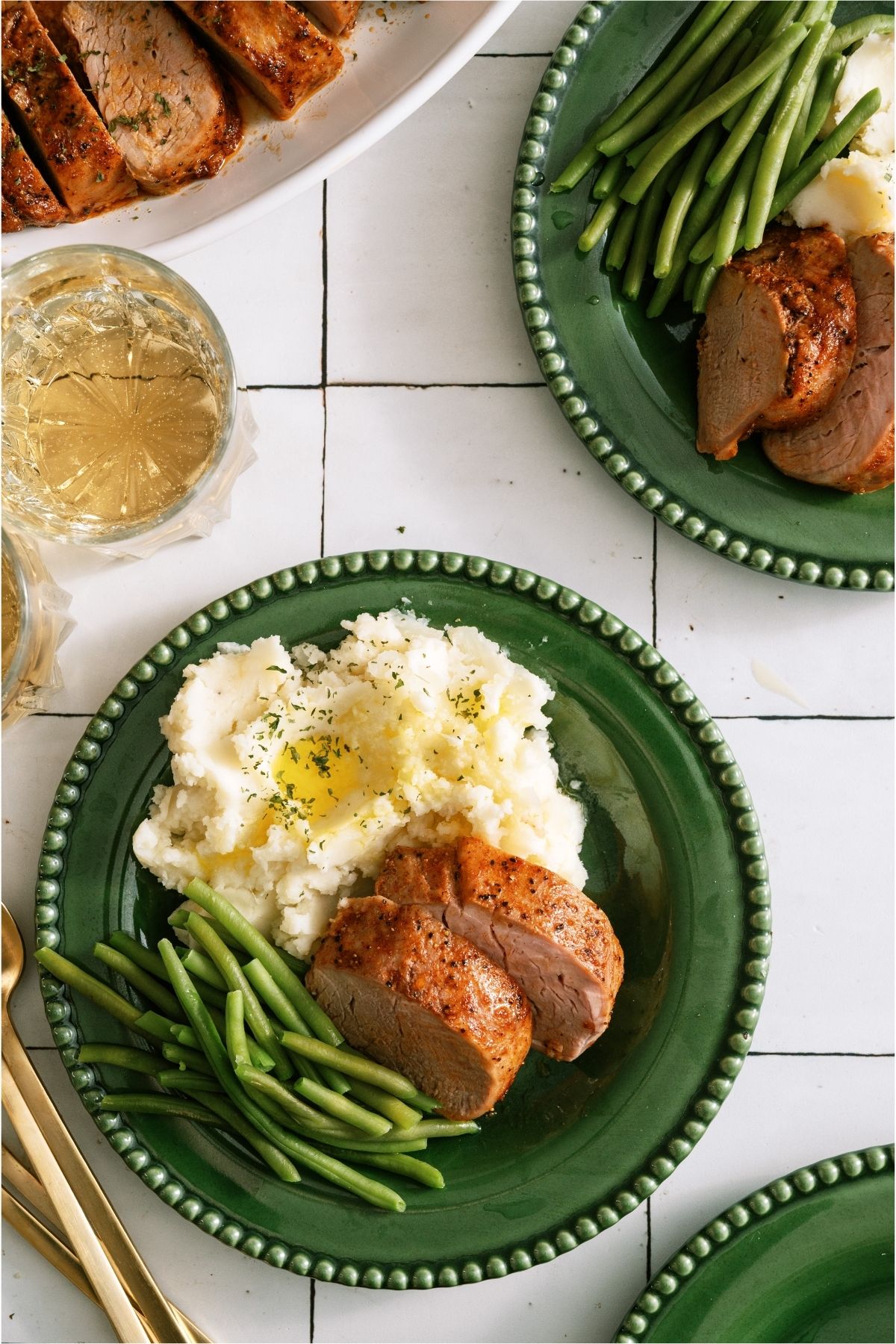 Top view of a plate with slices of Oven Baked Pork Tenderloin, mashed potatoes and green beans.