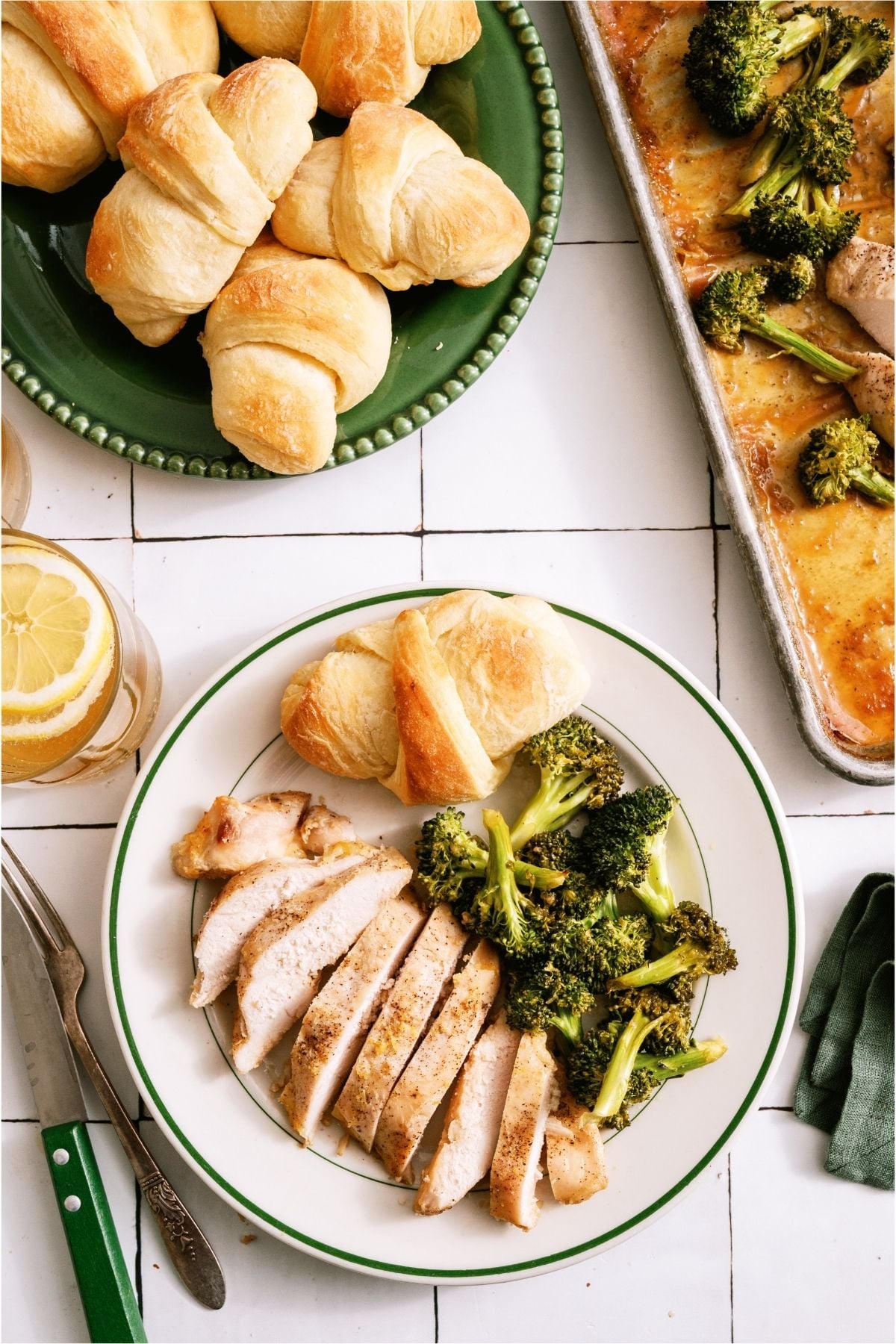 Sheet Pan Honey Lemon Chicken on a plate with broccoli and a roll.