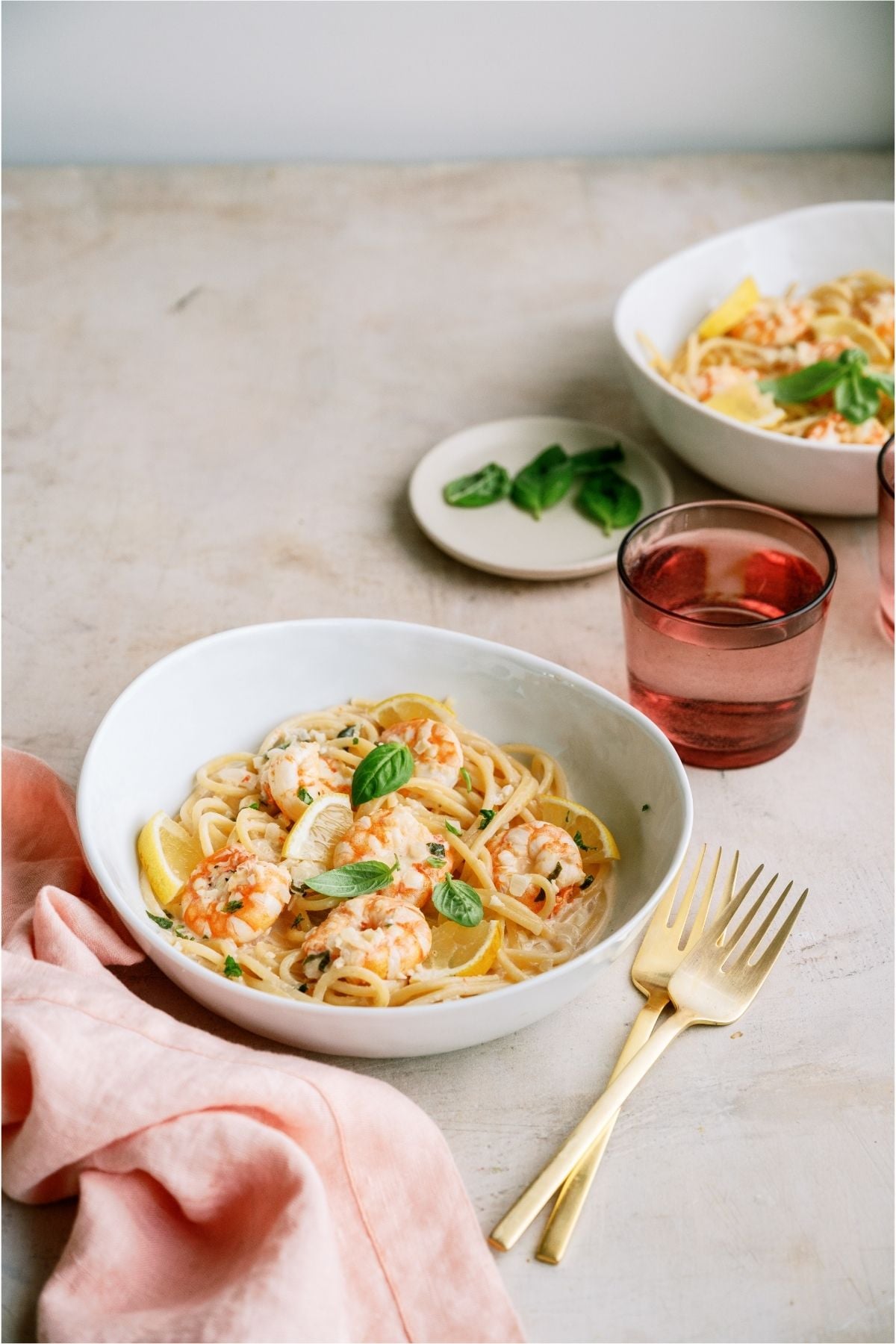 A serving of Lemon Garlic Shrimp Pasta in a bowl with a fork and cup on the side.