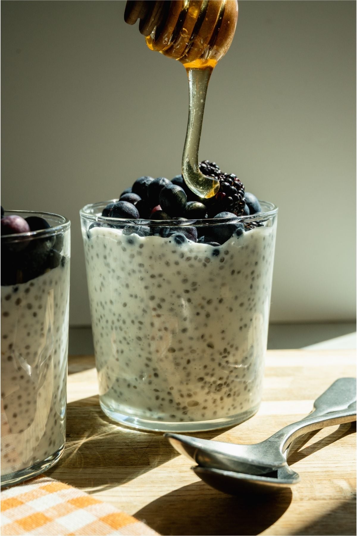 Drizzling honey on top of a glass of Overnight Chia Pudding.