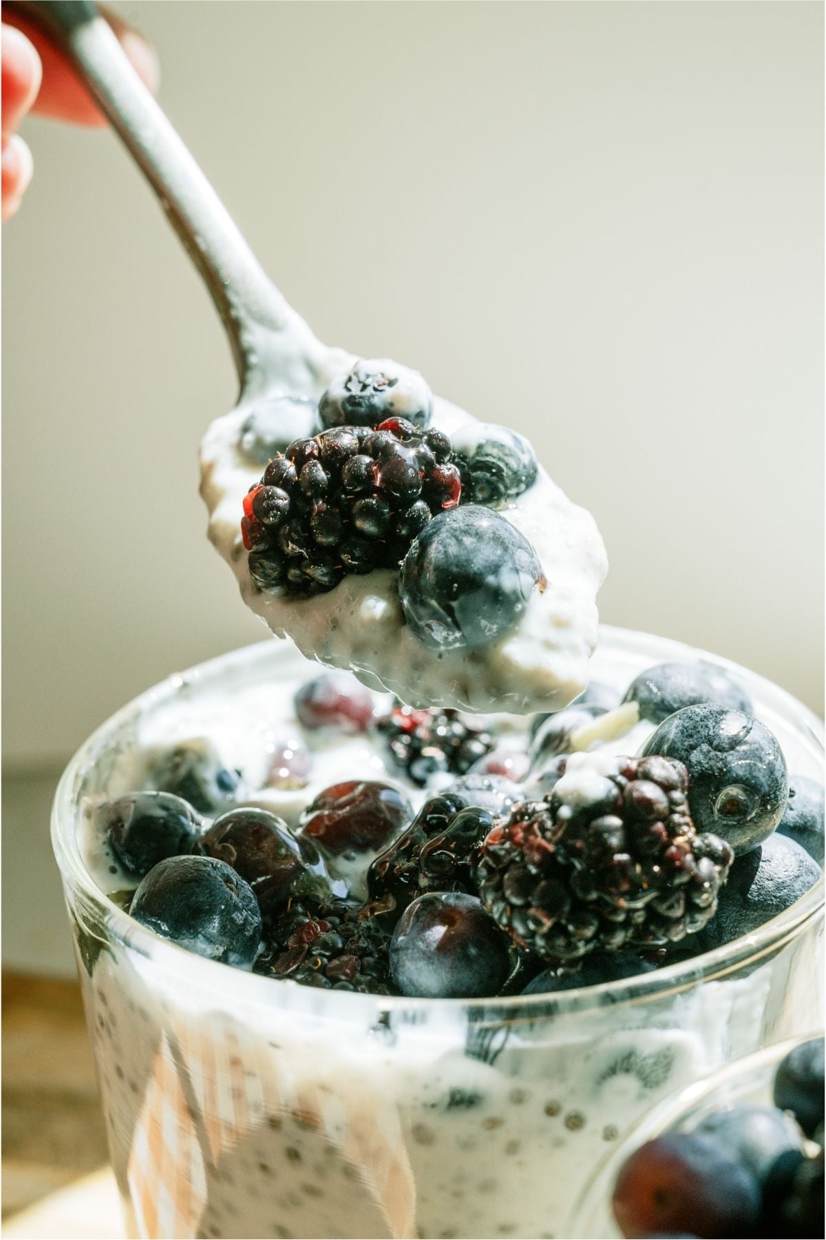 A spoon lifting a bite of Overnight Chia Pudding out of a glass.