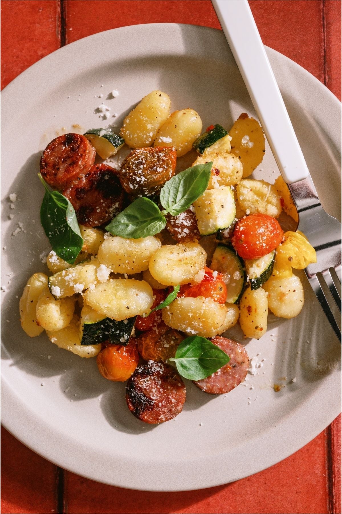 Top view of a serving of Sheet Pan Gnocchi and Chicken Sausage on a plate with a fork.
