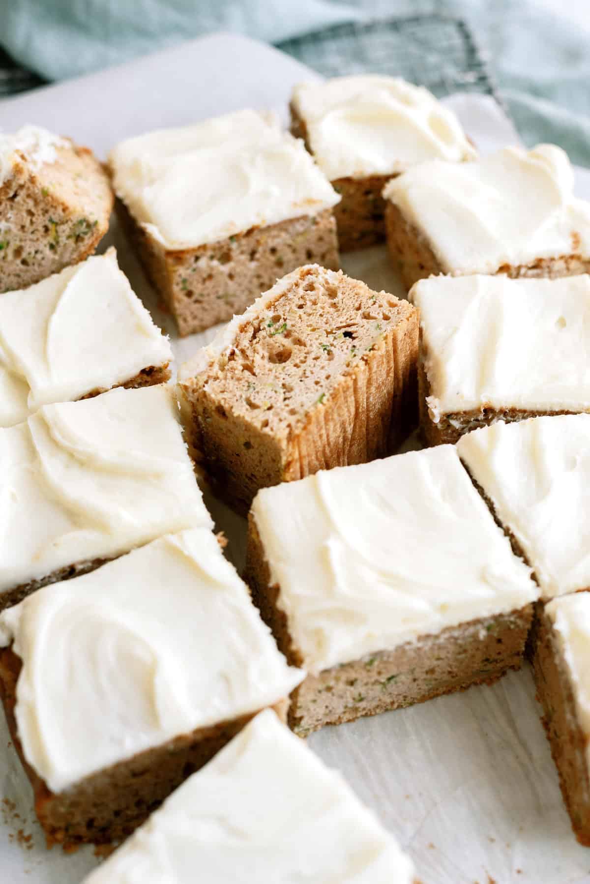 Sliced pieces of frosted cake arranged on a white surface, with one piece turned on its side showing the interior texture.