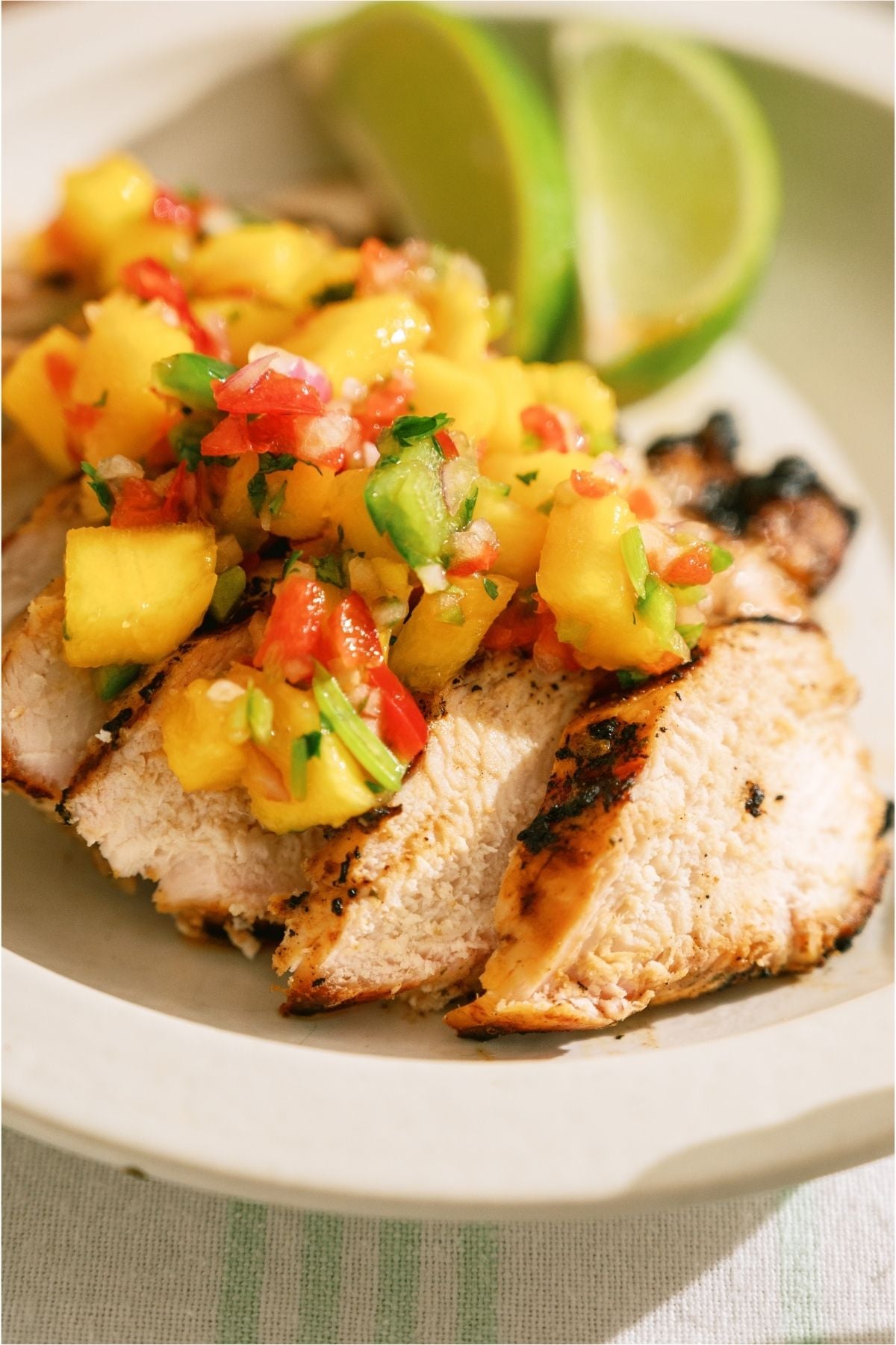 Grilled Mango Coconut Chicken sliced on a plate with lime wedges.