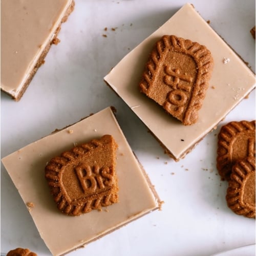 No Bake Biscoff Bars cut into squares with a broken biscoff cookie on top.