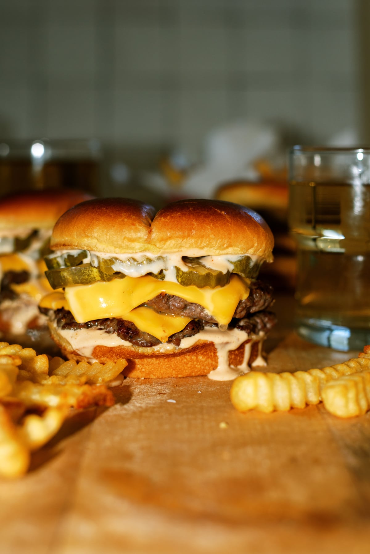 Assembled smash burger with double patties, a big helping of sauce, and served with a side of fries.