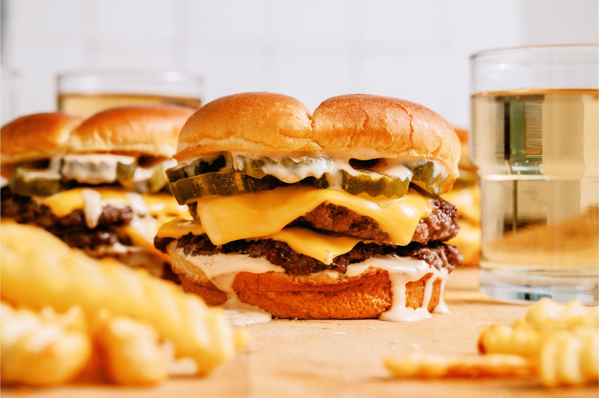 3 Smash Burgers with Shack Sauce on a countertop with fries.