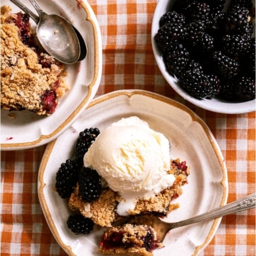 A serving of Blackberry Crumble on a plate topped with ice cream.